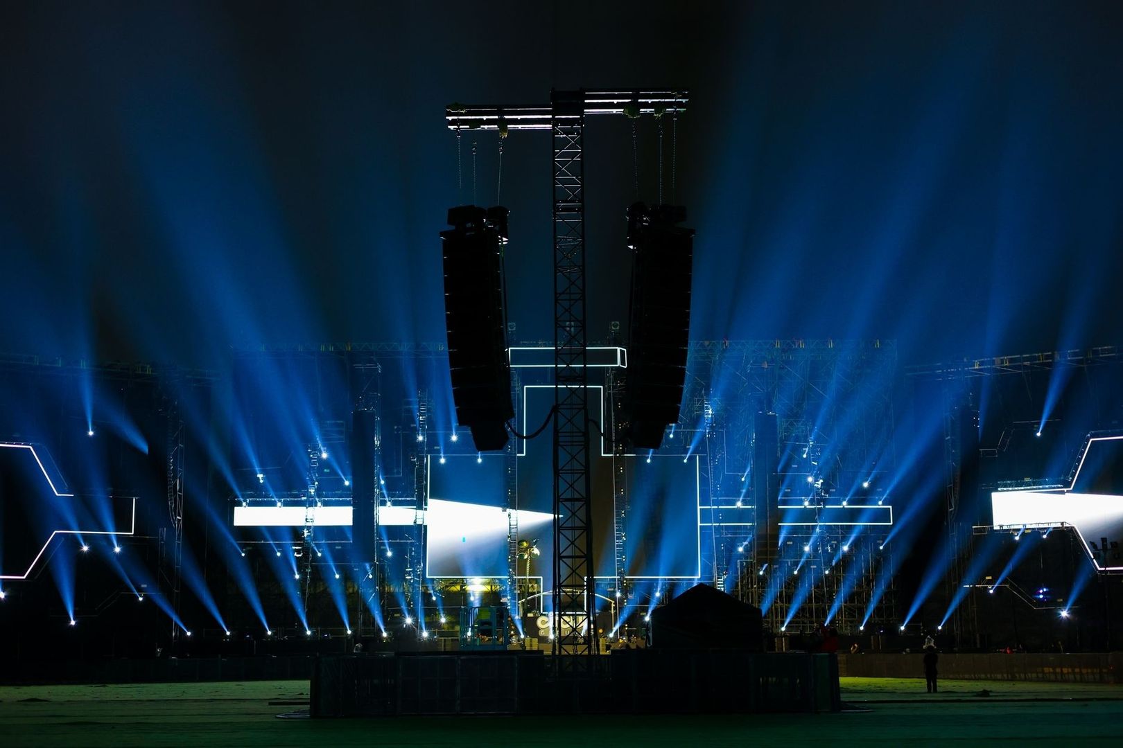 Concert stage with suspended line-array speakers and blue lights