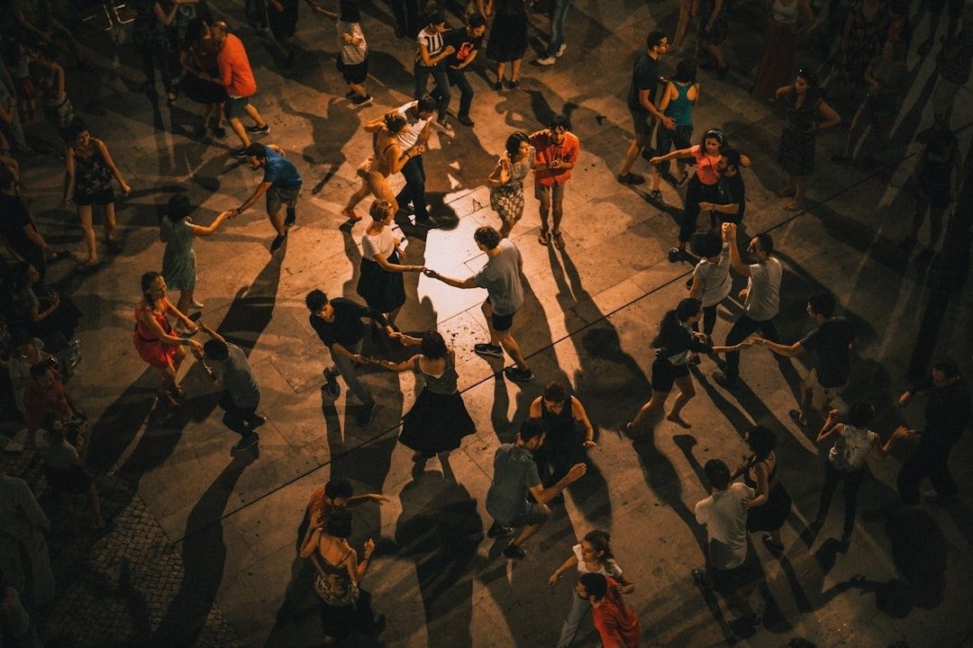A crowded outdoor dance gathering viewed from above, with many people dancing